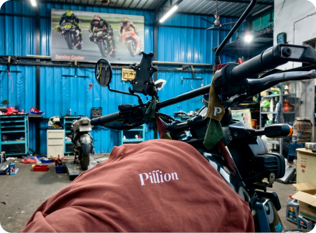 A Pillion t-shirt draped over a motorcycle inside a workshop.